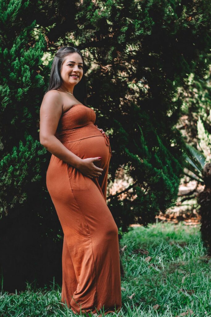 Pregnant woman in an orange dress outdoors, looking for Denver resources for pregnant and new parents